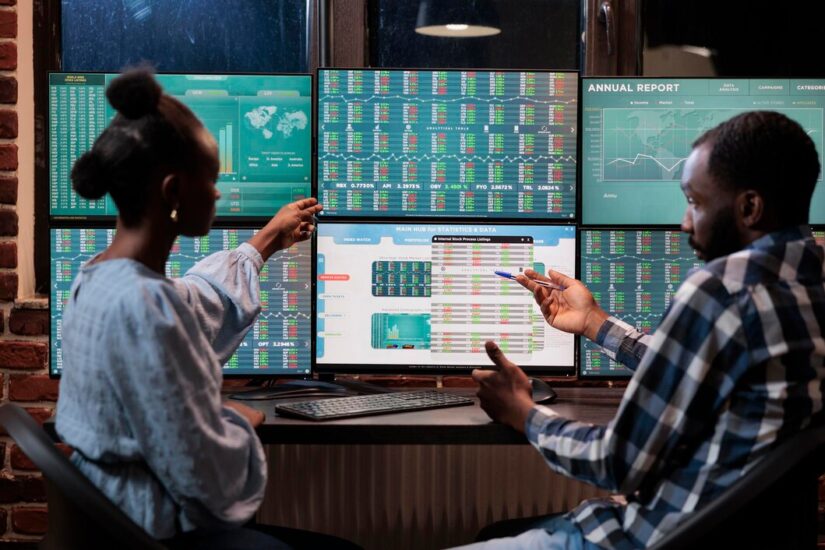 african-american-financial-advisors-reviewing-real-time-market-data-statistics-order-sell-stocks-hedge-fund-traders-sitting-workstation-while-pointing-display-with-live-index-charts_482257-40566